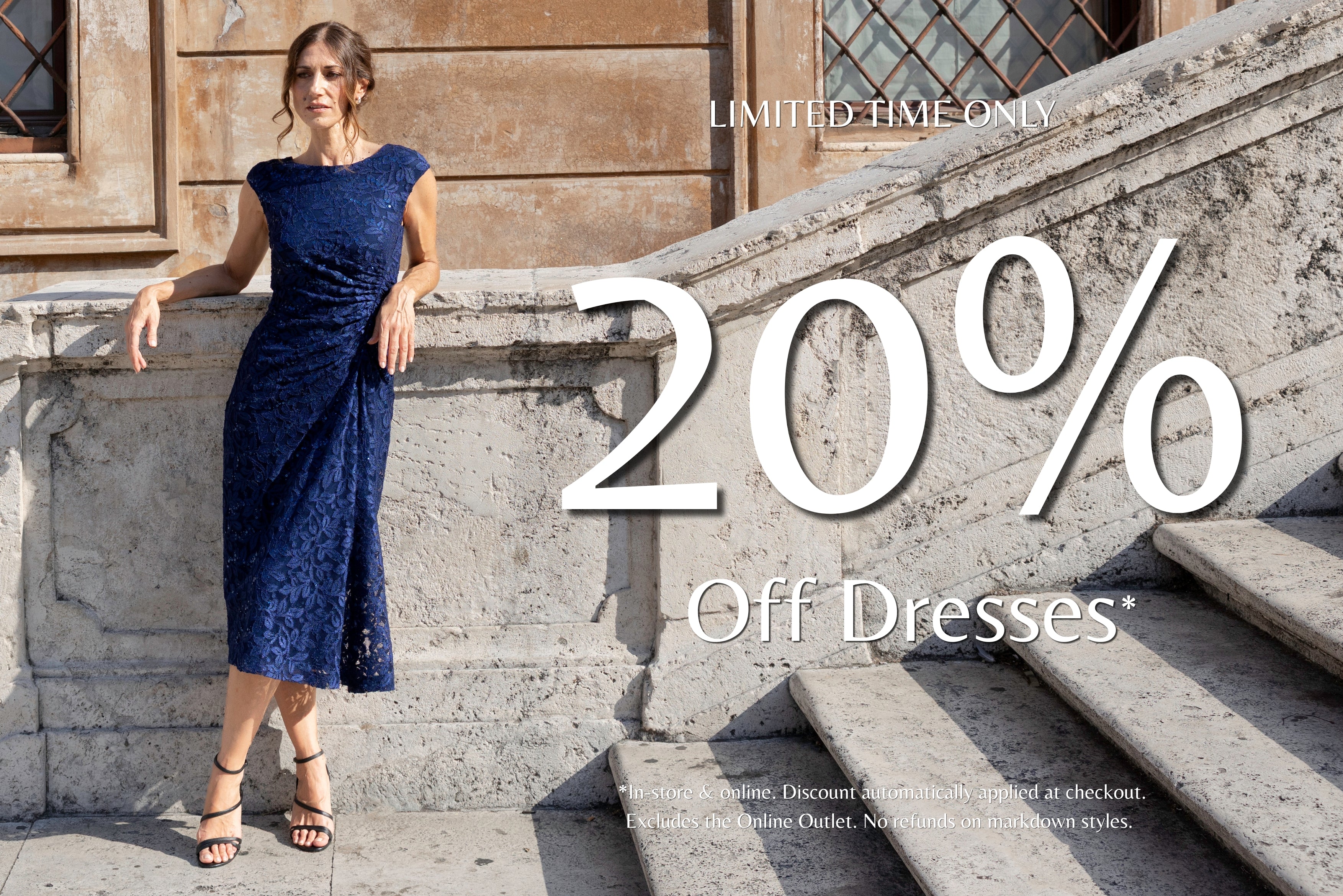 20% off dresses for a limited time at Anthea Crawford. Model wearing the Harriet Navy Lace Dress on stone steps.