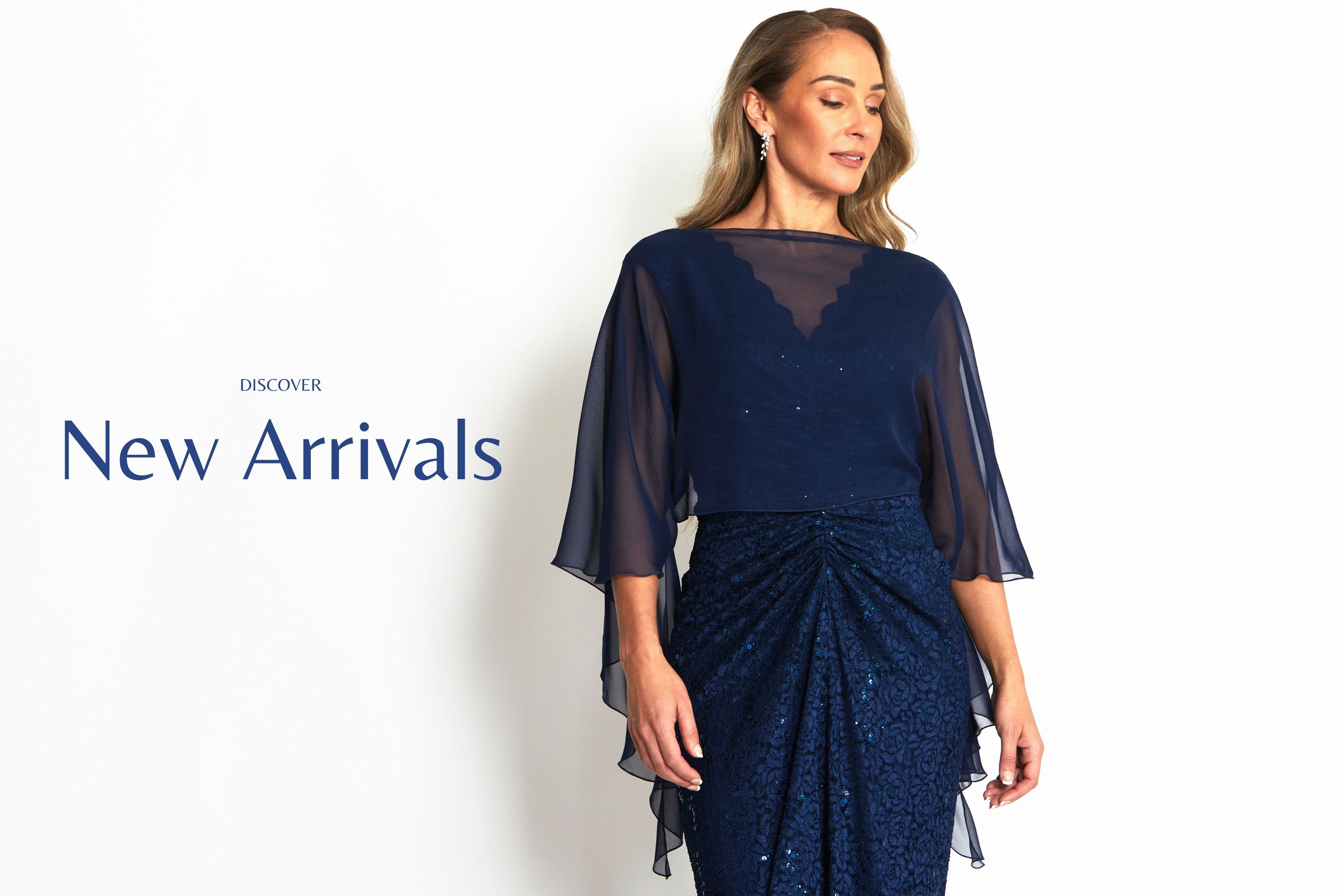 Woman wearing a navy blue dress with sheer sleeves on a white background, featuring 'New Arrivals' text. Yasmina Navy Lace Gown & Navy Silk Shrug
