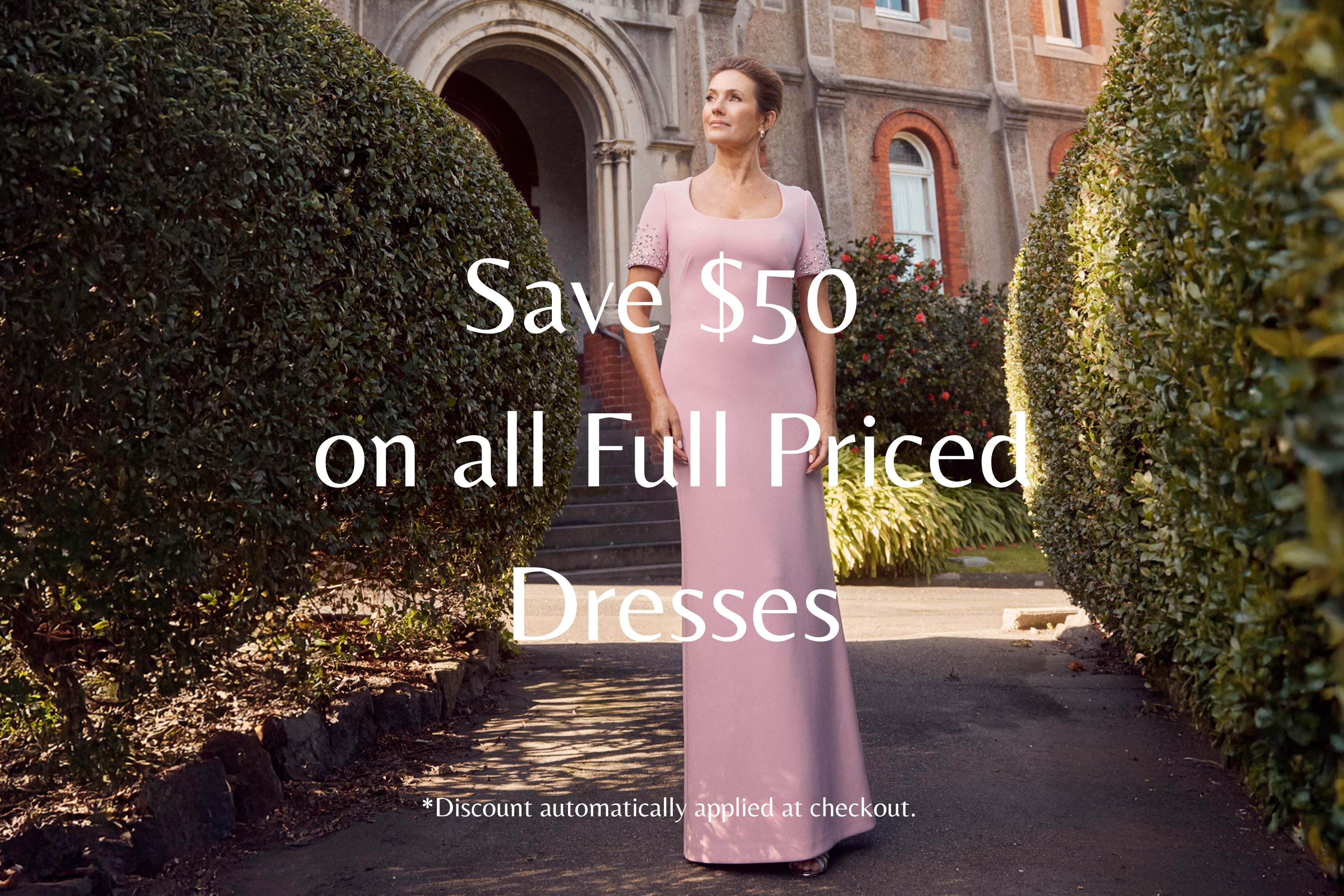 Woman in a pink dress standing in front of a building with text overlay about a discount on dresses. Save $50 on all Full Priced Dresses